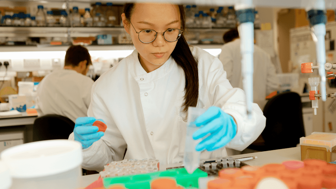 Scientist wearing blue gloves in a lab.